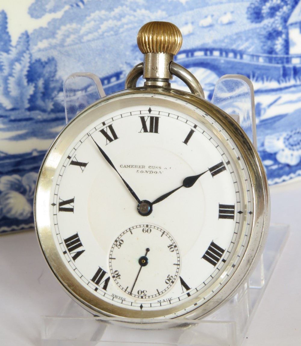 An open-face antique silver pocket watch featuring a white enamel dial with black Roman numerals and a subsidiary seconds sub-dial.