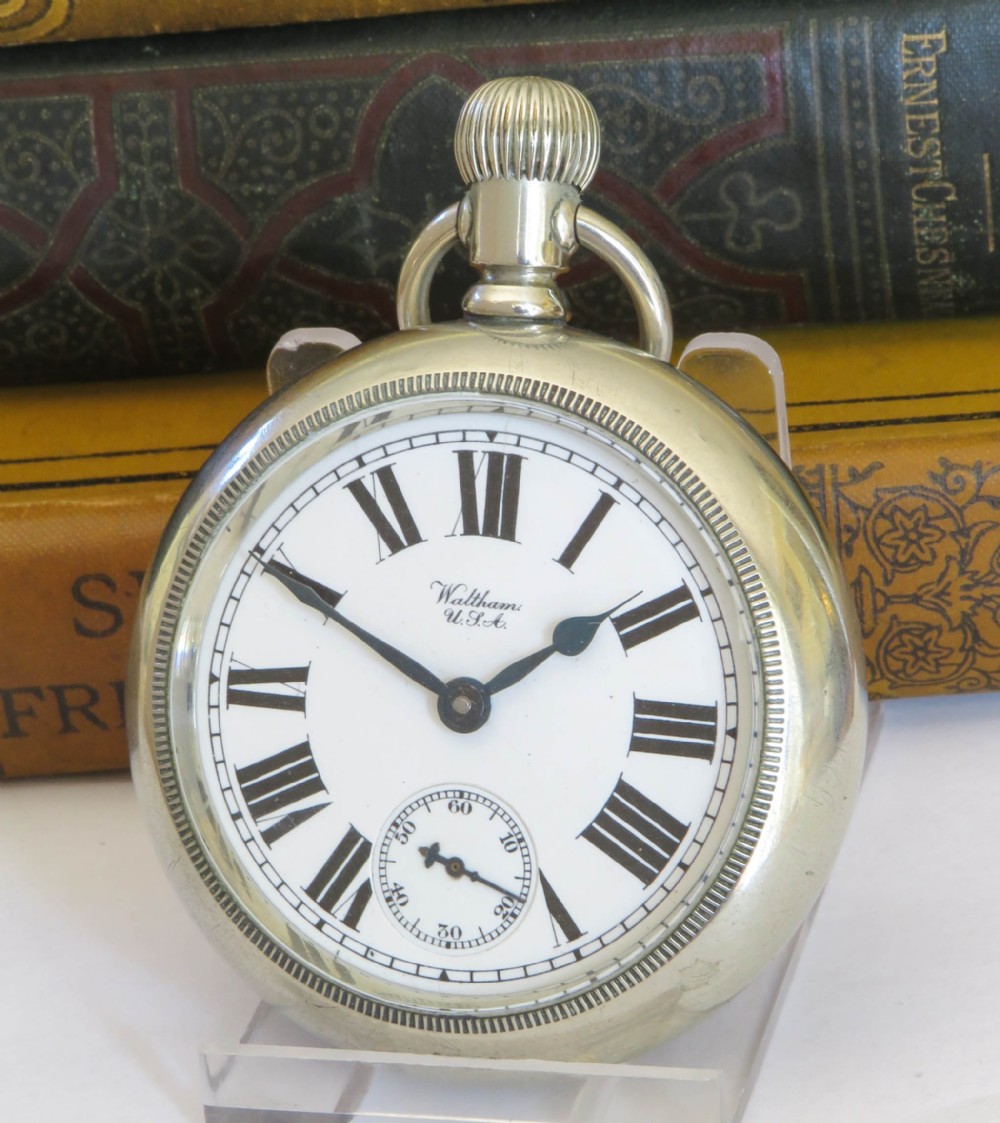 An antique silver-tone open-face pocket watch featuring a white enamel dial with black Roman numerals and a subsidiary seconds dial.