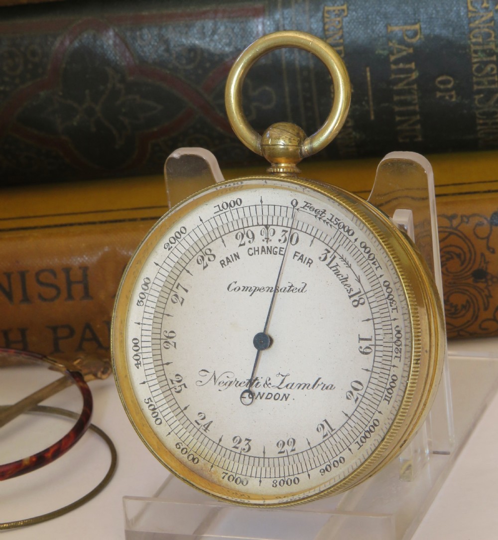 A Victorian brass pocket barometer by Negretti & Zambra featuring a calibrated white dial, central pointer, and top suspension ring.