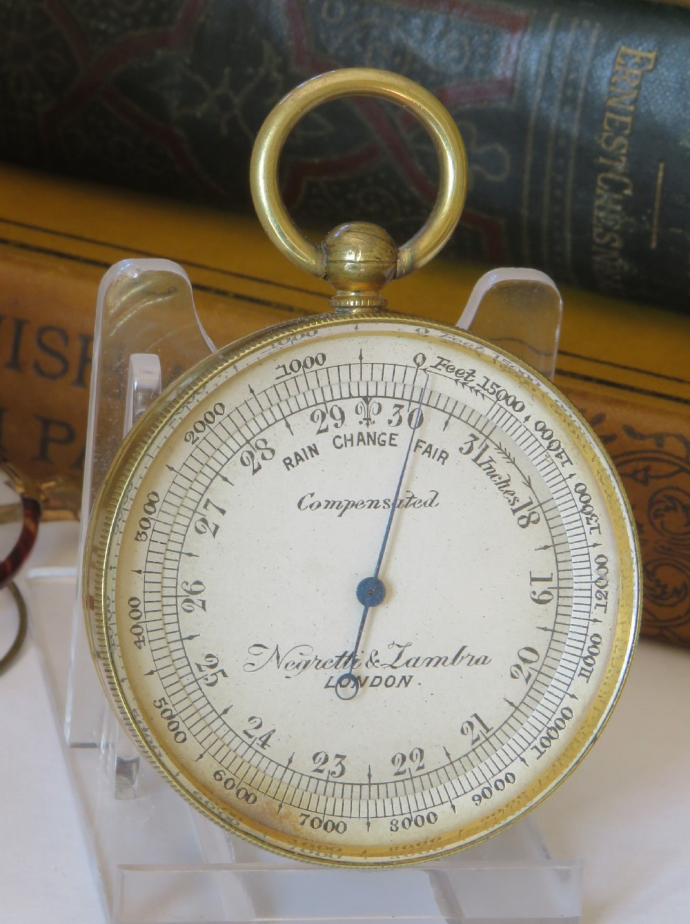 A Victorian brass pocket barometer by Negretti & Zambra featuring a calibrated white dial, central pointer, and top suspension ring. View II