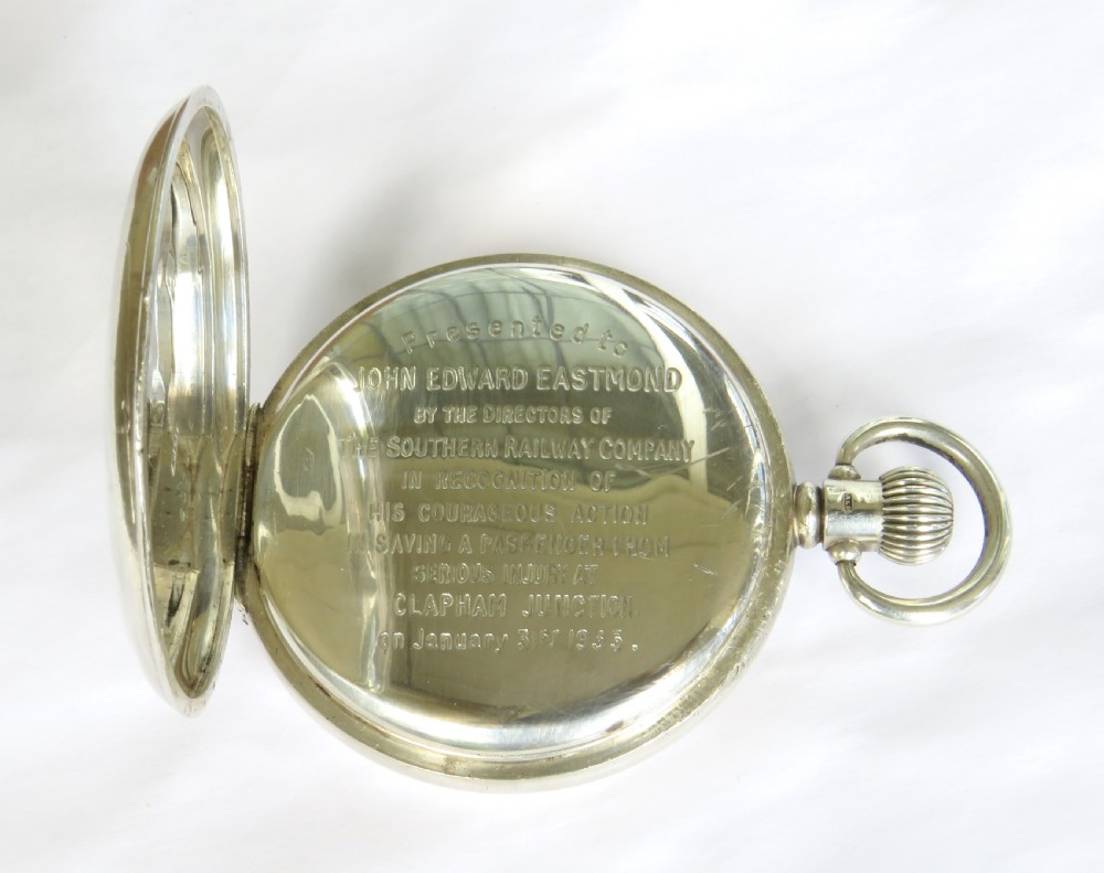 A 1930s silver hunter pocket watch featuring a open hinged cover, a white enamel dial with black Arabic numerals, and a sub-seconds display at six oclock. View IV