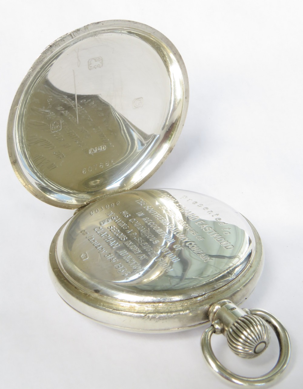 A 1930s silver hunter pocket watch featuring a open hinged cover, a white enamel dial with black Arabic numerals, and a sub-seconds display at six oclock. View V