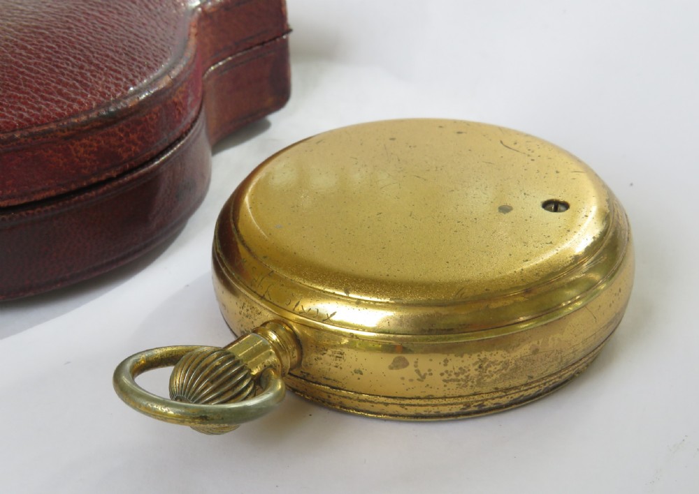 An antique brass pocket barometer and altimeter shown inside an open burgundy leather travel case lined with green velvet. View III