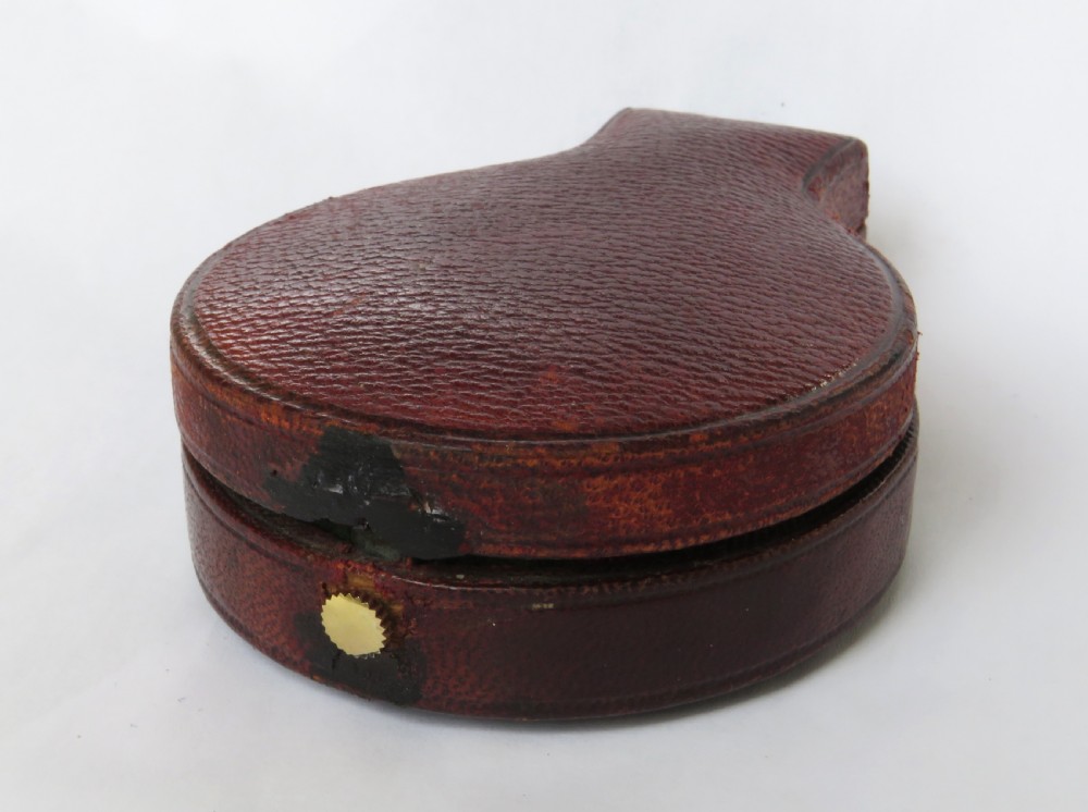 An antique brass pocket barometer and altimeter shown inside an open burgundy leather travel case lined with green velvet. View IV