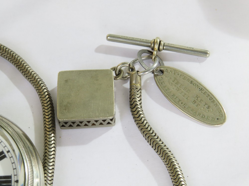 An open face 1930s silver pocket watch with Roman numerals and a subsidiary seconds dial, attached to a flexible snake chain Albert with a square compass fob. View VI