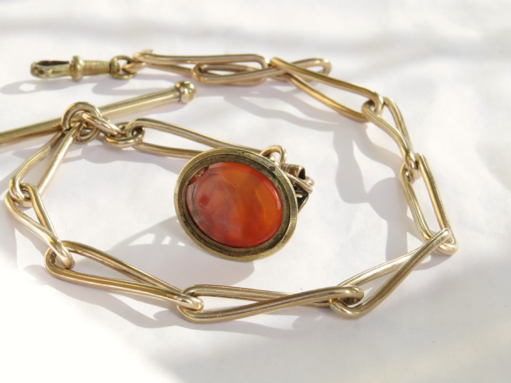 An antique 1920s rolled rose gold watch Albert chain featuring elongated trombone links, a T-bar, swivel clasp, and a carved carnelian fob pendant. View III