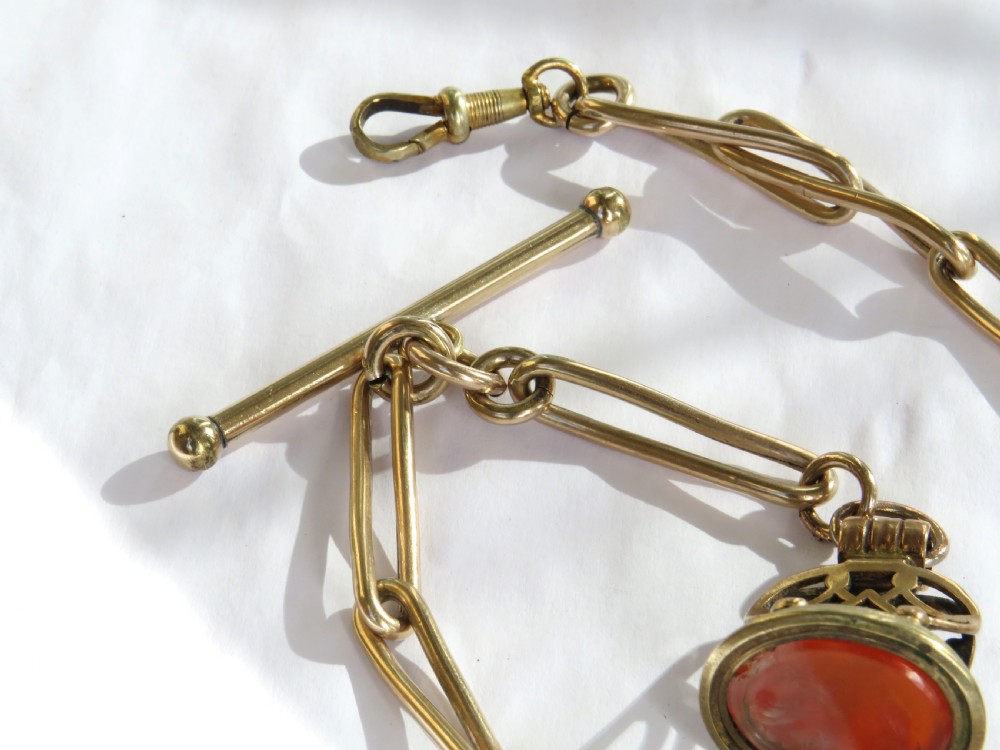 An antique 1920s rolled rose gold watch Albert chain featuring elongated trombone links, a T-bar, swivel clasp, and a carved carnelian fob pendant. View IV