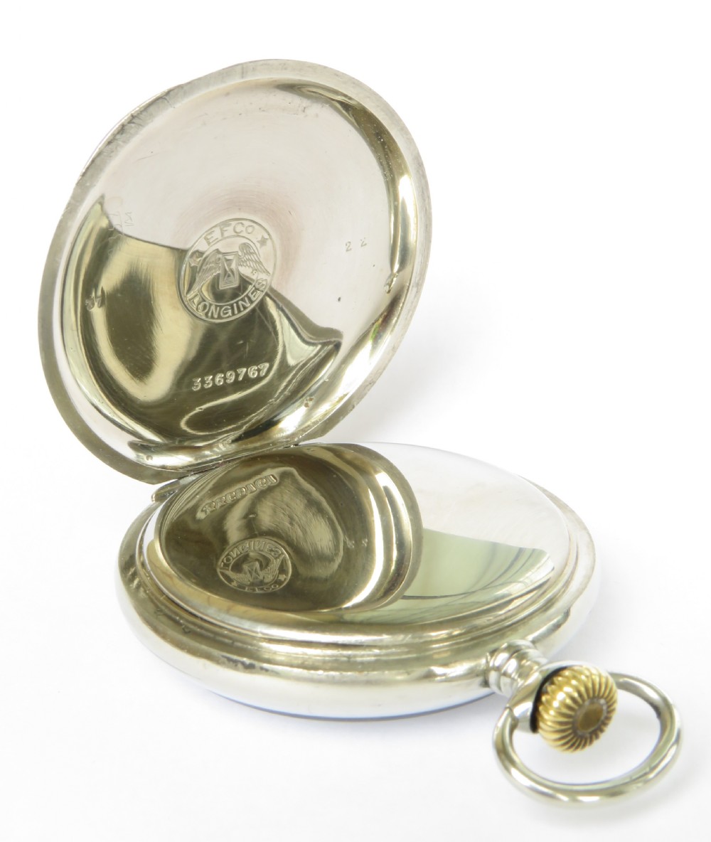 An antique open face Longines pocket watch featuring a white enamel dial with black Arabic numerals, a sub-seconds dial, and a silver casing with a brass crown. View III