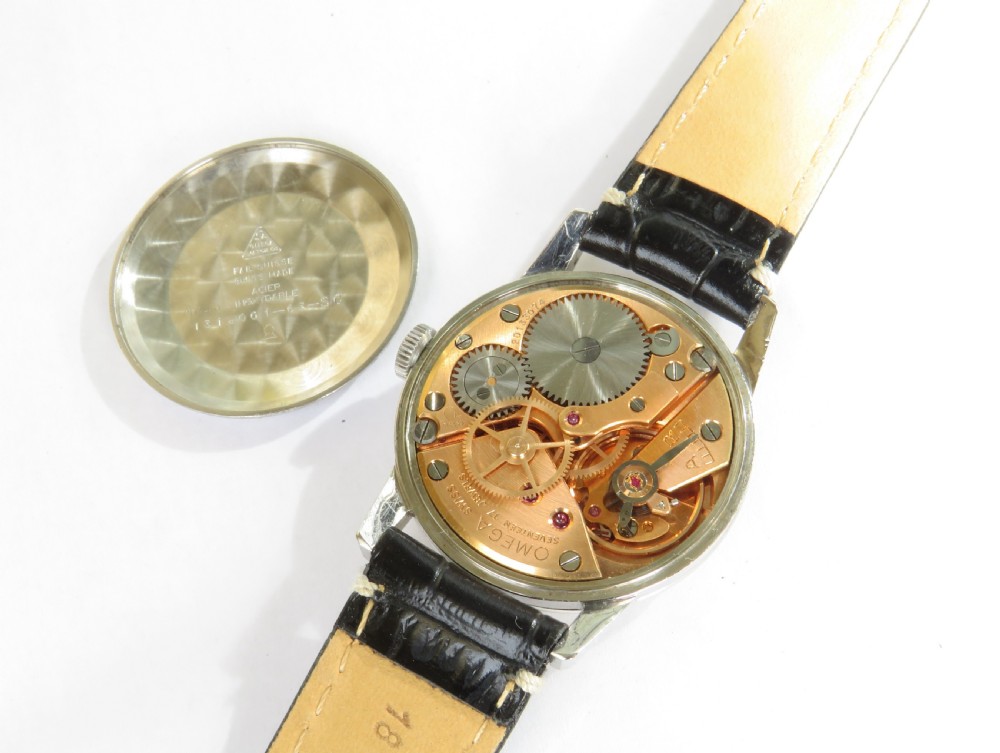 A 1963 mens Omega wrist watch featuring a round stainless steel case, a cream dial with Arabic numerals, and a black leather strap with white stitching. View III