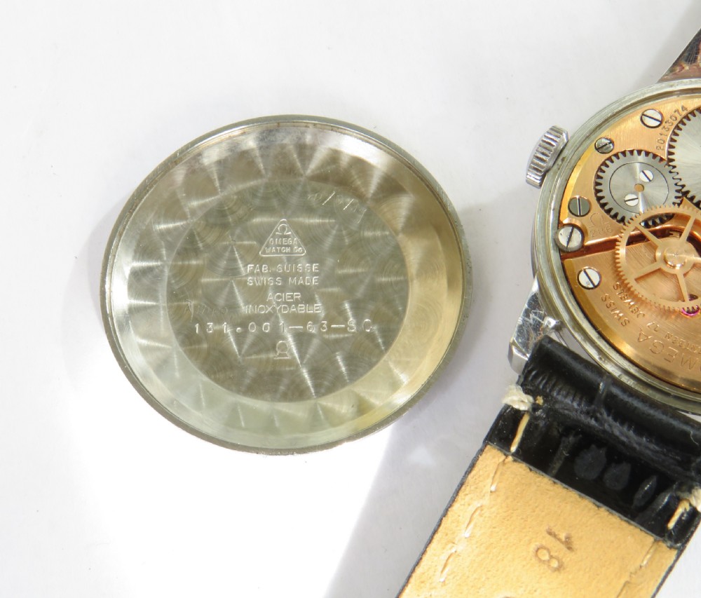 A 1963 mens Omega wrist watch featuring a round stainless steel case, a cream dial with Arabic numerals, and a black leather strap with white stitching. View IV