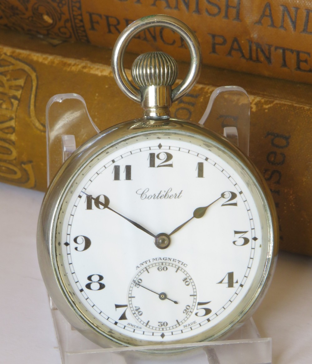 An open-face 1930s Cortebert Swiss pocket watch with a white enamel dial, black Arabic numerals, sub-seconds register, and a polished silver-toned metal case. View II