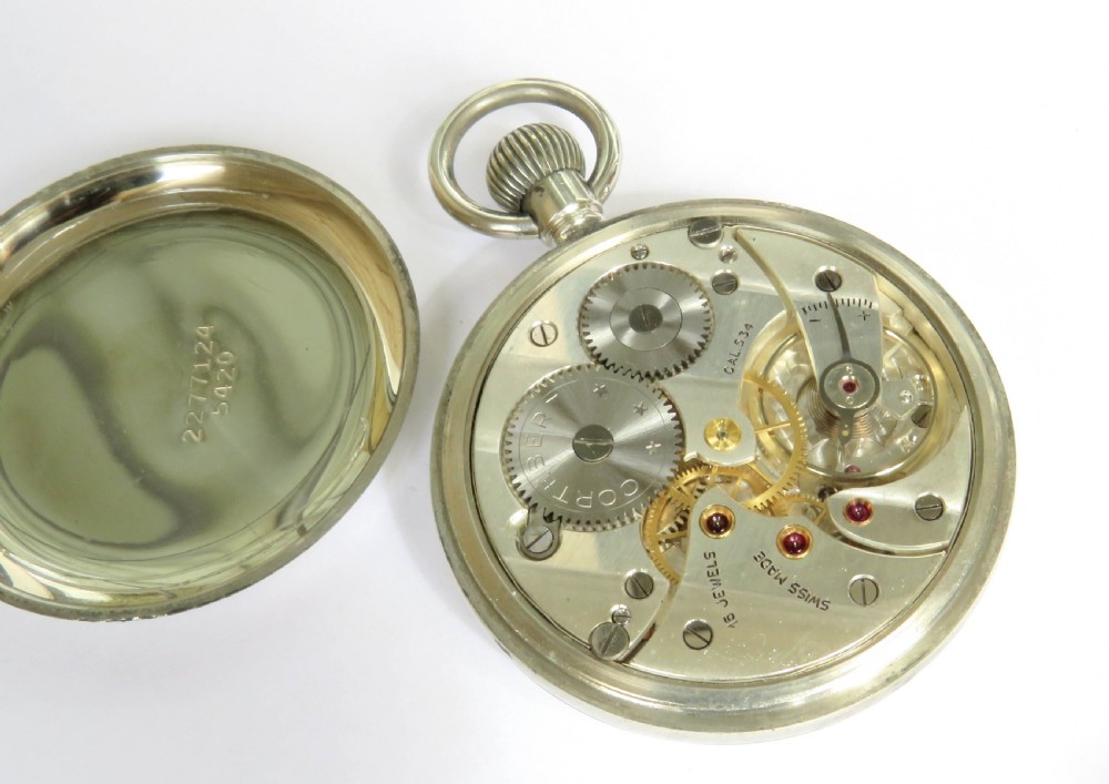 An open-face 1930s Cortebert Swiss pocket watch with a white enamel dial, black Arabic numerals, sub-seconds register, and a polished silver-toned metal case. View III