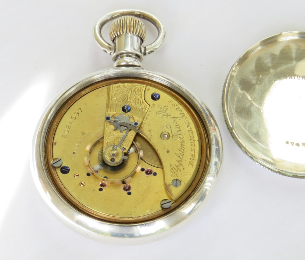 An open-face silver pocket watch featuring a white enamel dial with black Roman numerals, red minute tracking, a subsidiary seconds dial, and blued steel hands. View III