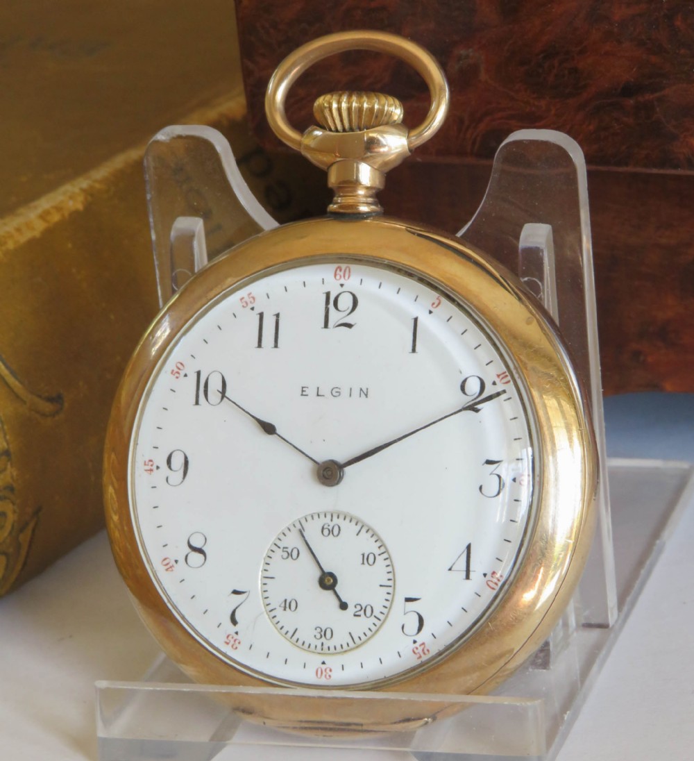 An Edwardian open-face gold-filled Elgin pocket watch featuring a white enamel dial with black Arabic numerals and a subsidiary seconds dial.