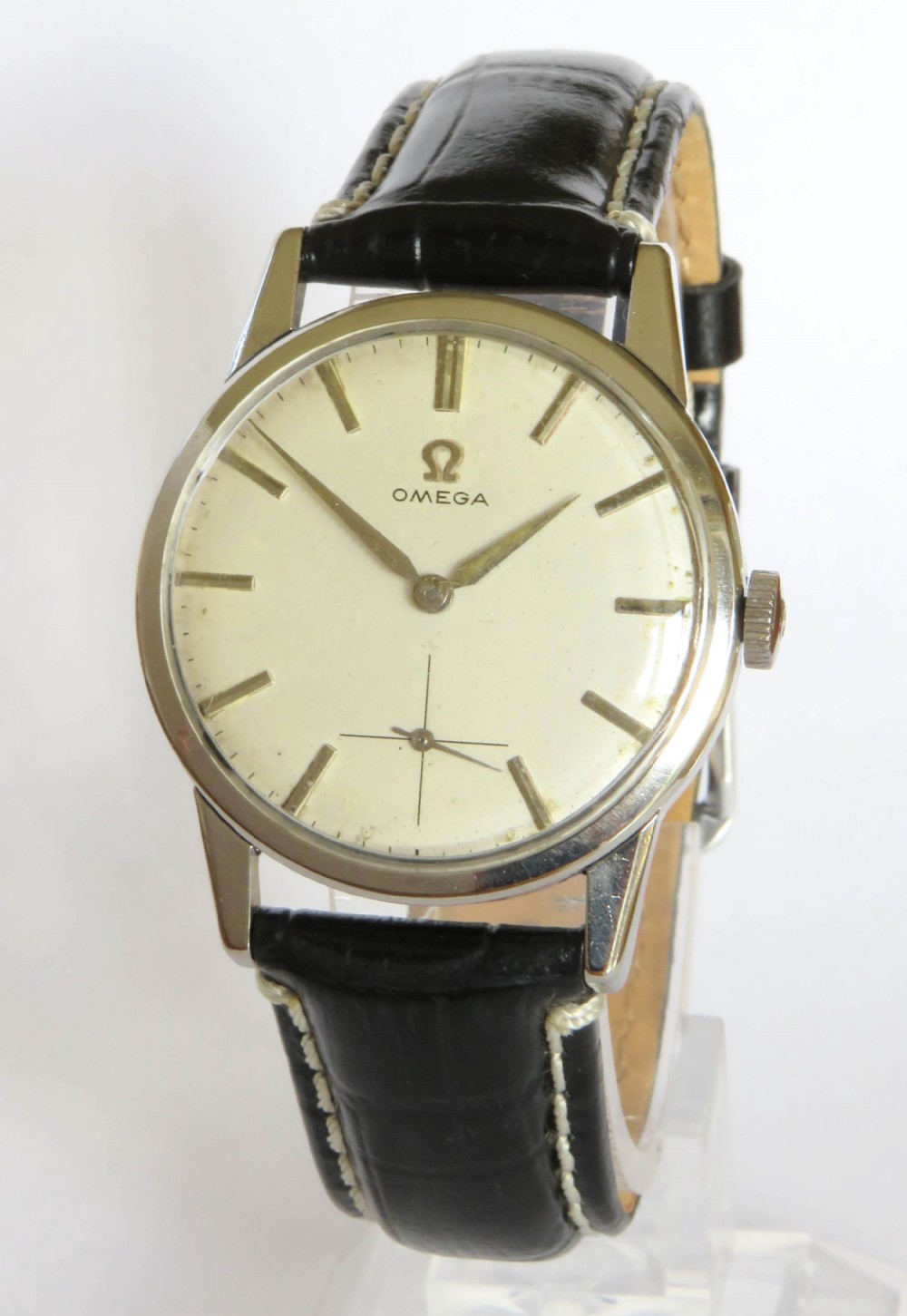A 1960s gents Omega wristwatch with a round stainless steel case, a cream dial featuring baton markers and a sub-seconds dial, paired with a stitched black leather strap.
