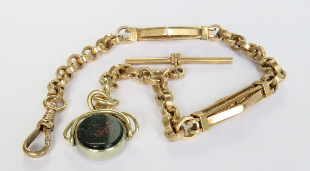 An antique rolled gold pocket watch chain with a T-bar, swivel clasp, openwork links, and a spinning seal fob set with a red stone. View II