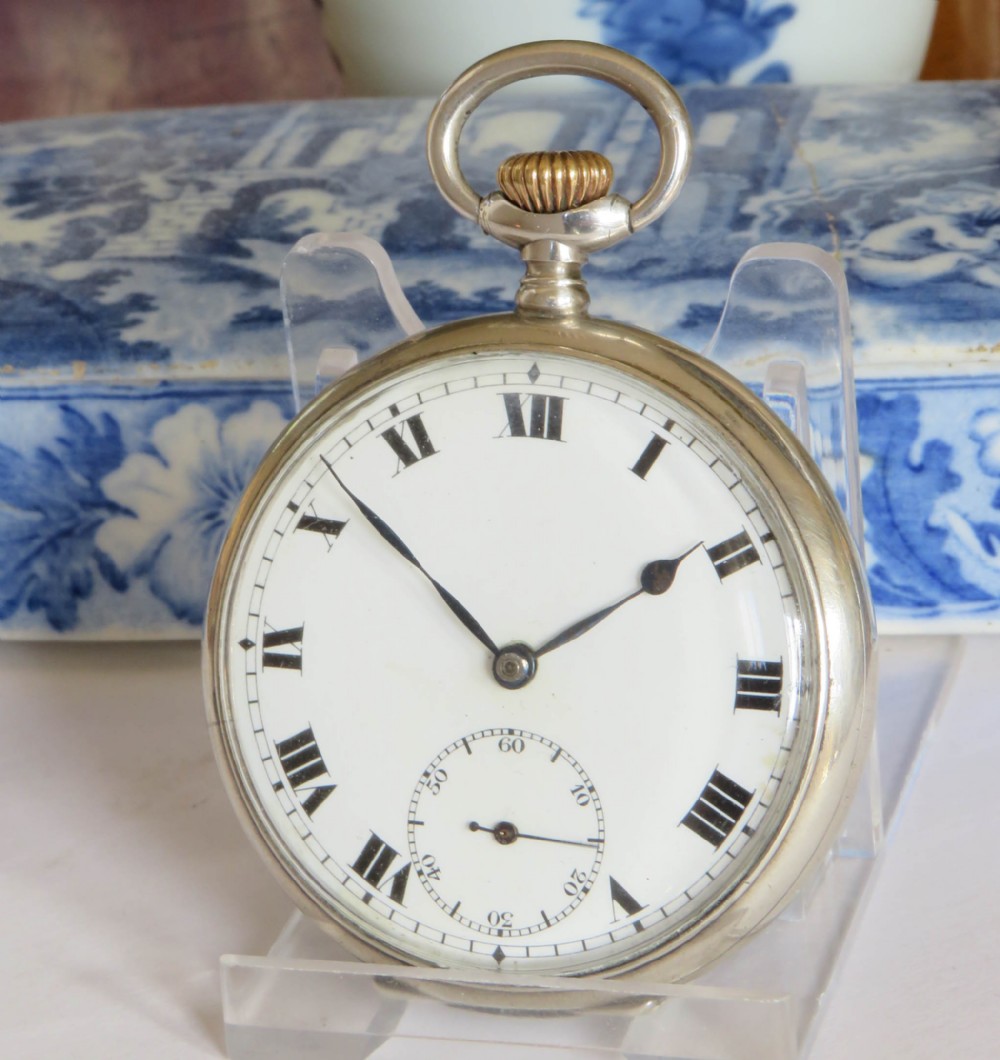 An open-face antique Swiss silver pocket watch featuring a white enamel dial with black Roman numerals and a subsidiary seconds sub-dial.