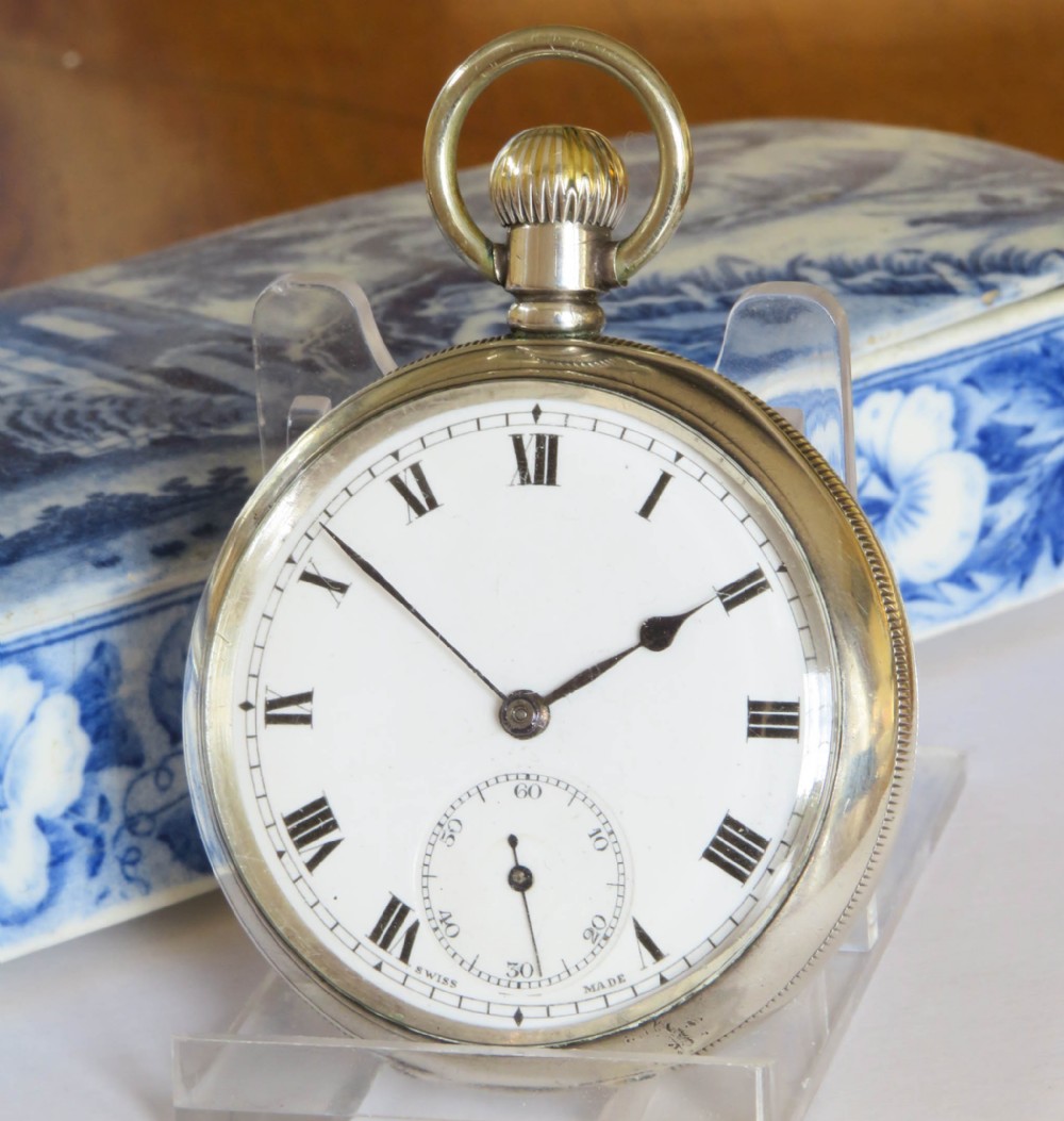 An antique open-face silver pocket watch displaying a white enamel dial with black Roman numerals and a small seconds sub-dial at six oclock.