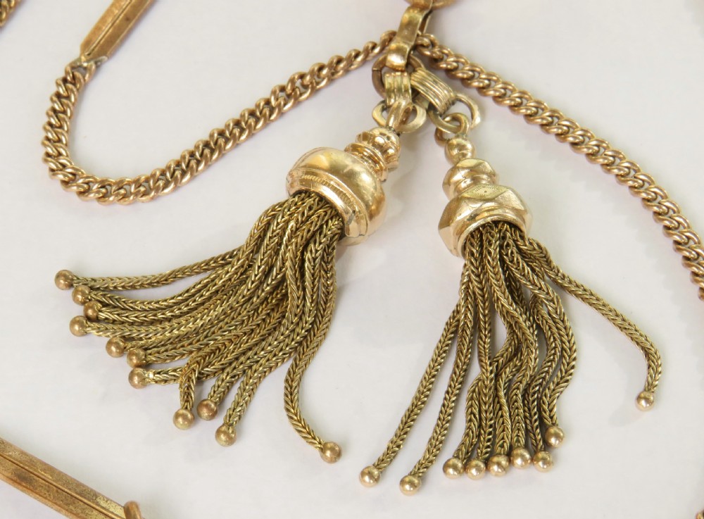 An Edwardian rolled gold double Albert pocket watch chain featuring curb links, decorative bar sections, swivel clasps, a central bolt ring, and two suspended tassels. View II