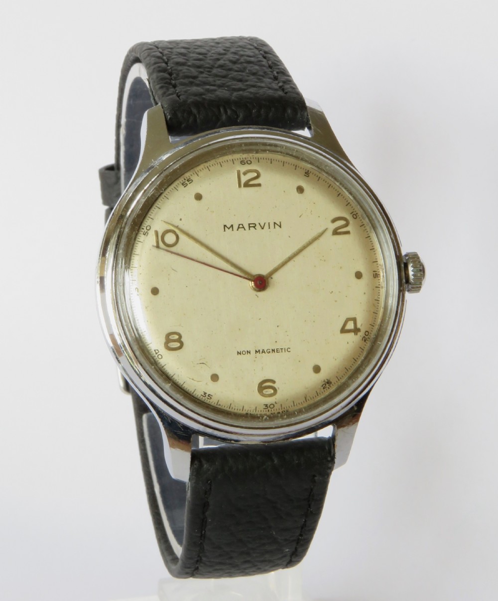 A 1950s gents Marvin wrist watch featuring a cream dial with Arabic numerals, a stainless steel case, and a textured black leather strap. View II