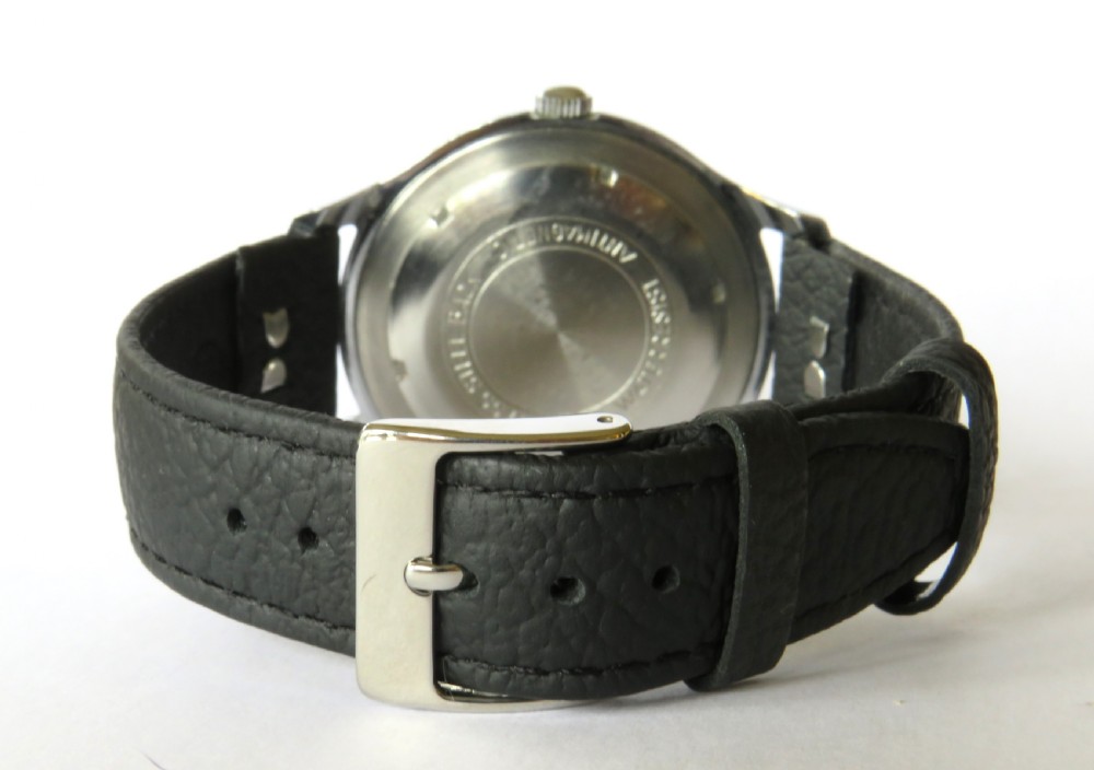A 1950s gents Marvin wrist watch featuring a cream dial with Arabic numerals, a stainless steel case, and a textured black leather strap. View V
