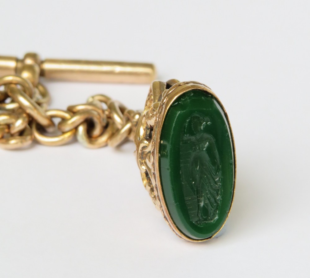 An antique rolled gold curb link Albert watch chain featuring a T-bar, swivel clasp, bolt ring, and a suspended fob with a green oval stone intaglio. View IV