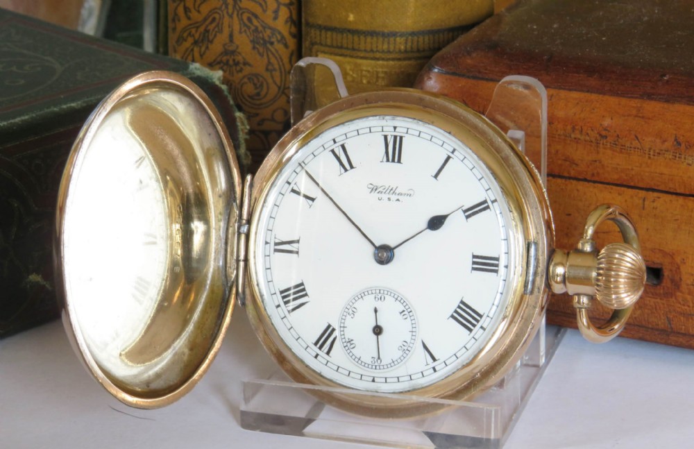 An open gold full hunter pocket watch displaying a white enamel dial with black Roman numerals and a small seconds subdial.