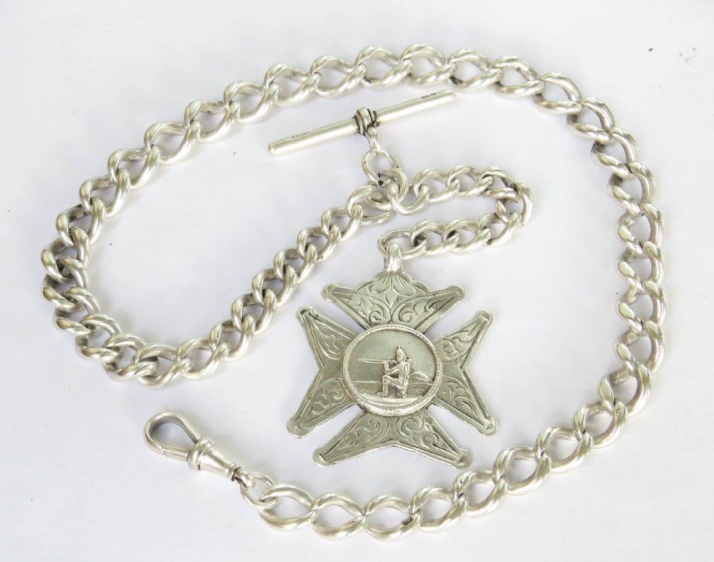 An Edwardian sterling silver curb-link pocket watch chain featuring a T-bar, a swivel clasp, and a medallion fob engraved with a marksman design.