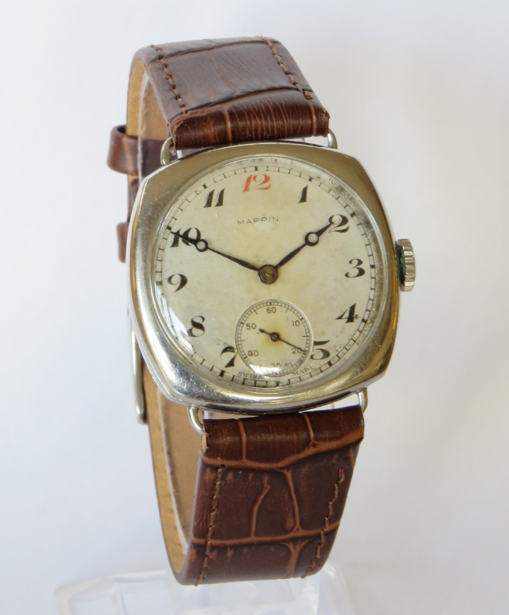 A 1930s cushion-shaped stainless steel wristwatch featuring a light dial with black Arabic numerals, a red twelve marker, a subsidiary seconds dial, and a textured brown leather strap. View II