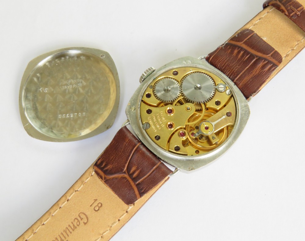 A 1930s cushion-shaped stainless steel wristwatch featuring a light dial with black Arabic numerals, a red twelve marker, a subsidiary seconds dial, and a textured brown leather strap. View III