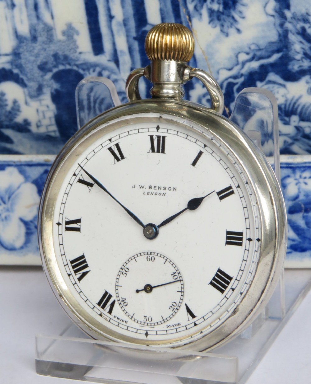 An antique open-face silver pocket watch featuring a white enamel dial with black Roman numerals and a subsidiary seconds dial.
