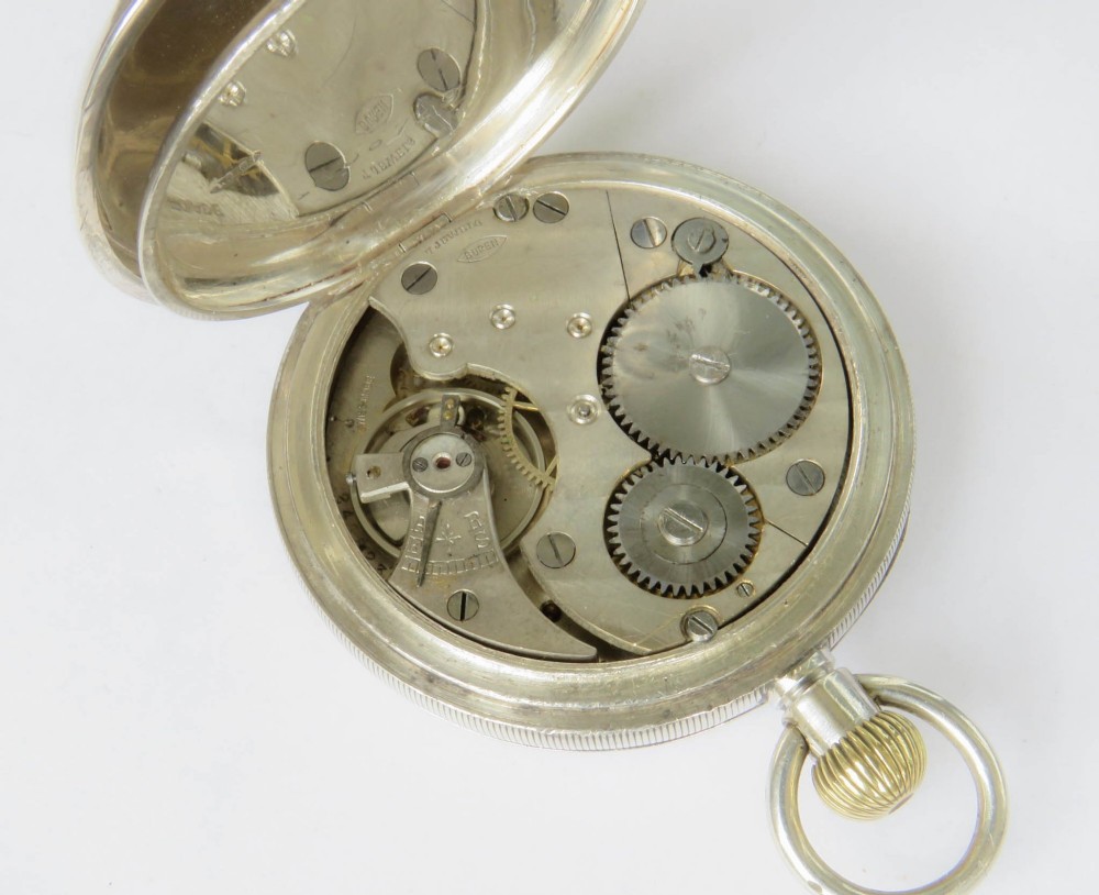 An open-face silver pocket watch featuring a white enamel dial with black Roman numerals, a sub-seconds dial at the bottom, and a brass winding crown at the top. View IV