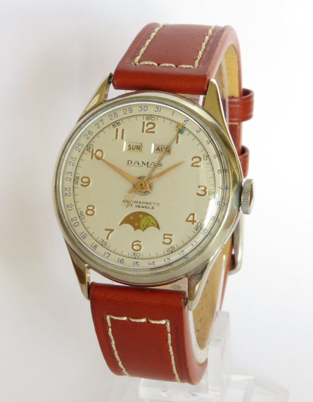 A 1950s Damas gents wrist watch featuring a cream dial with day, month, pointer date, and moonphase complications on a brown leather strap.