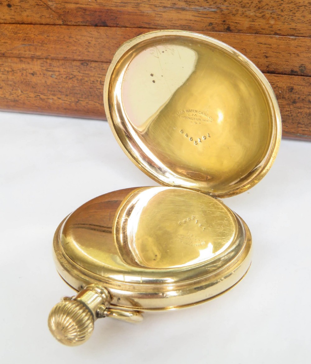 A gold-toned Waltham half hunter pocket watch with Roman numerals engraved around the central circular dial aperture. View IV