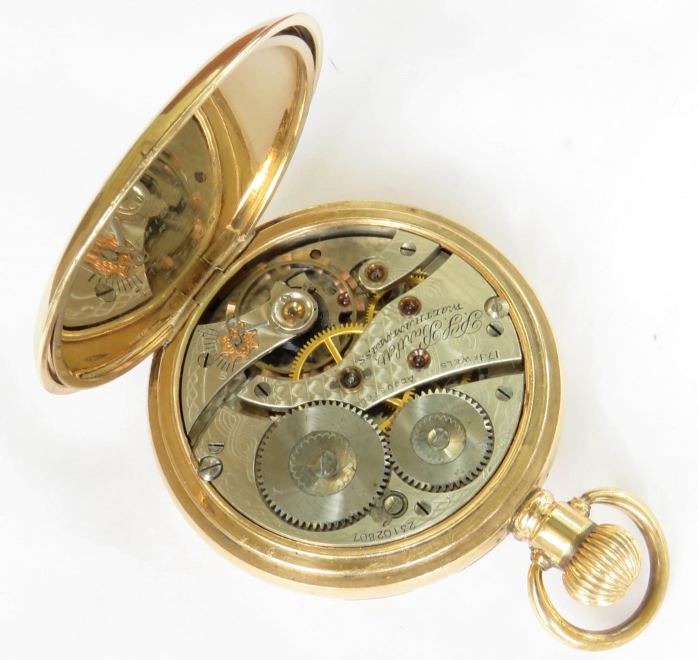 A gold-toned Waltham half hunter pocket watch with Roman numerals engraved around the central circular dial aperture. View V