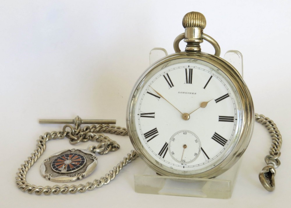 An antique open-face Longines pocket watch with a white enamel Roman numeral dial, connected to a silver-coloured curb chain with an enamelled fob medallion. View II