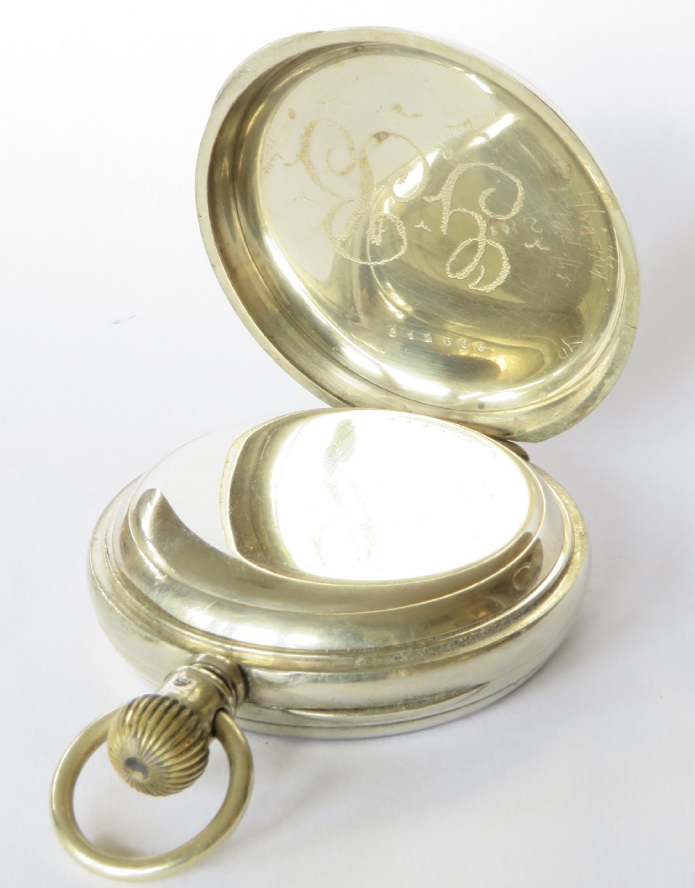 An antique open-face Longines pocket watch with a white enamel Roman numeral dial, connected to a silver-coloured curb chain with an enamelled fob medallion. View VI