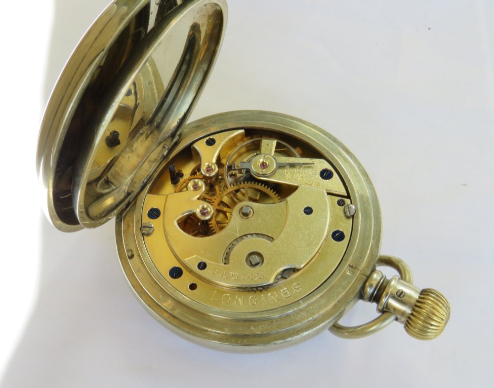An antique open-face Longines pocket watch with a white enamel Roman numeral dial, connected to a silver-coloured curb chain with an enamelled fob medallion. View VII