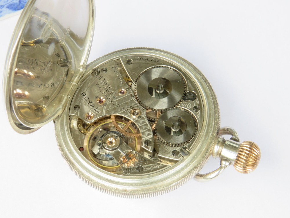 An open-face antique silver pocket watch featuring a white enamel dial with black Arabic numerals, a sub-seconds dial, and a ribbed gold-toned crown. View IV
