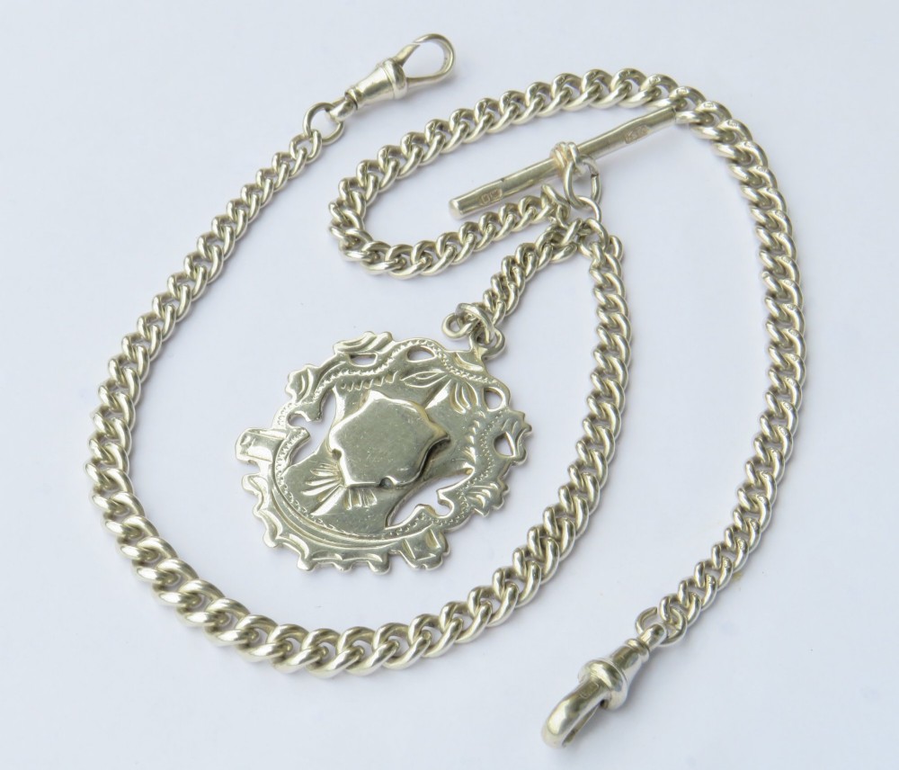An antique sterling silver single Albert pocket watch chain with curb links, T-bar, swivel clasps, and a central shield-shaped fob.
