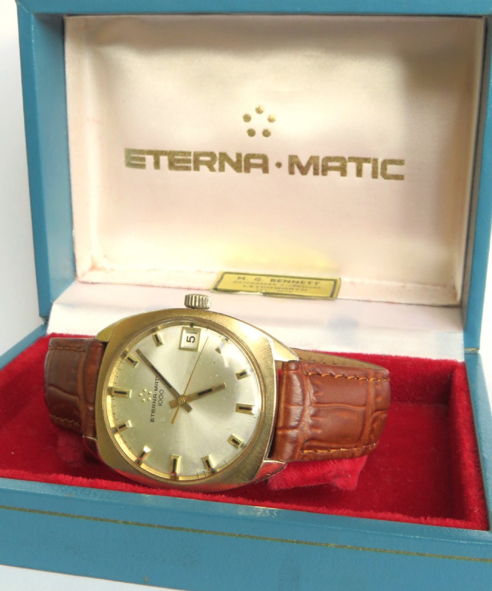A 1969 gents Eterna-Matic 1000 wristwatch featuring a gold-toned cushion case, champagne dial with date aperture, and brown leather strap. View III