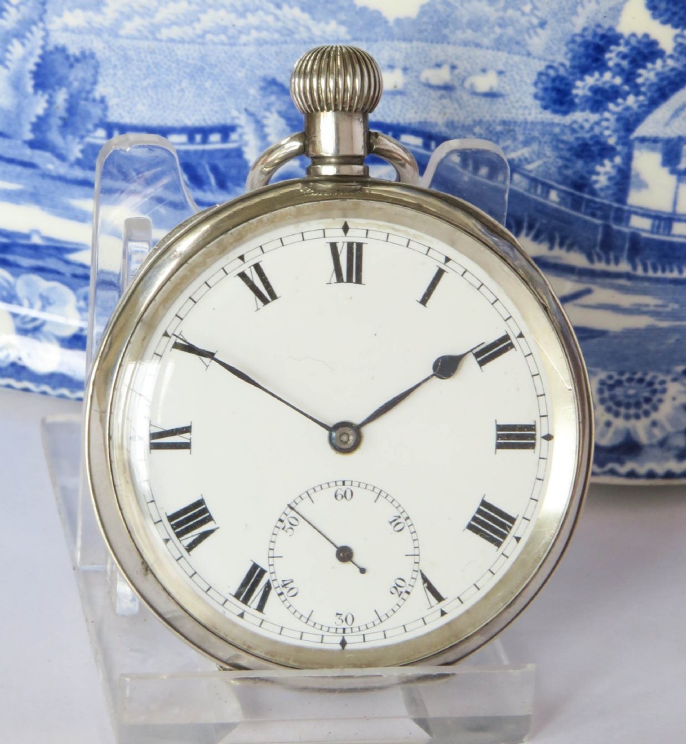 An open-face silver pocket watch displaying a white enamel dial with black Roman numerals and a subsidiary seconds sub-dial. View II