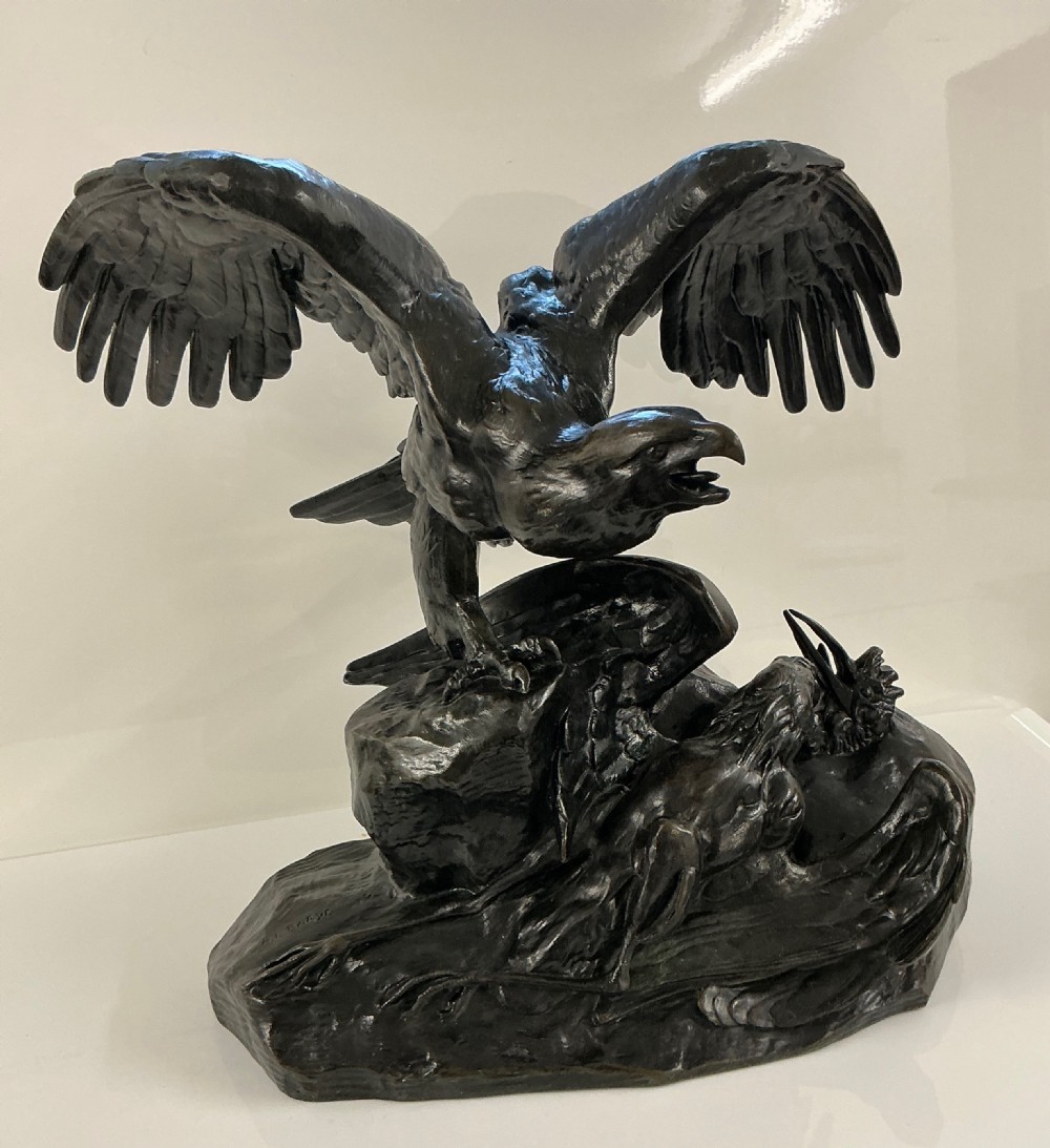A dark patinated bronze sculpture depicting an eagle with outstretched wings perched on a rocky base above a second bird.