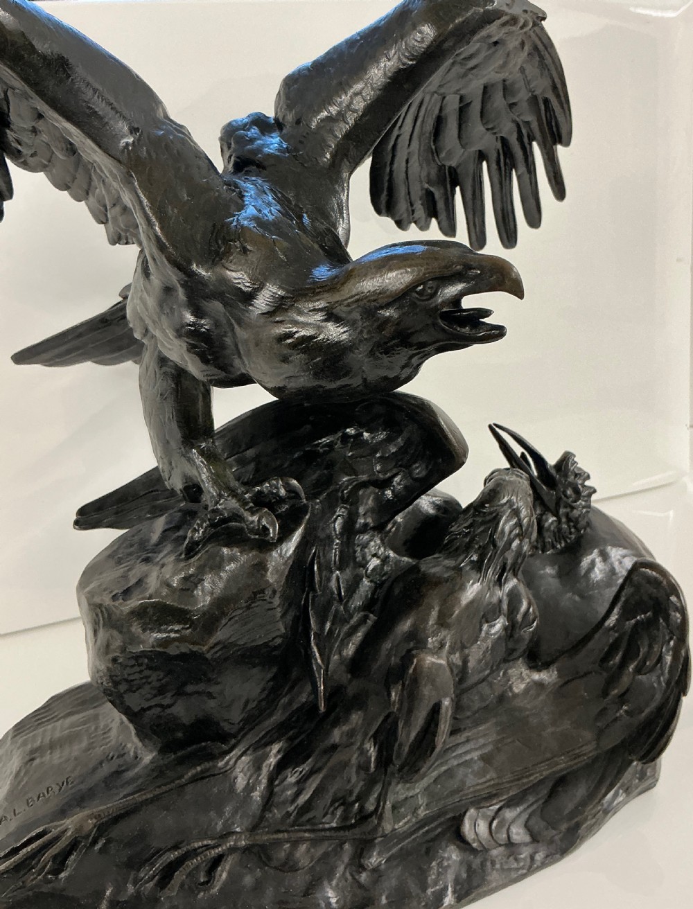 A dark patinated bronze sculpture depicting an eagle with outstretched wings perched on a rocky base above a second bird. View III