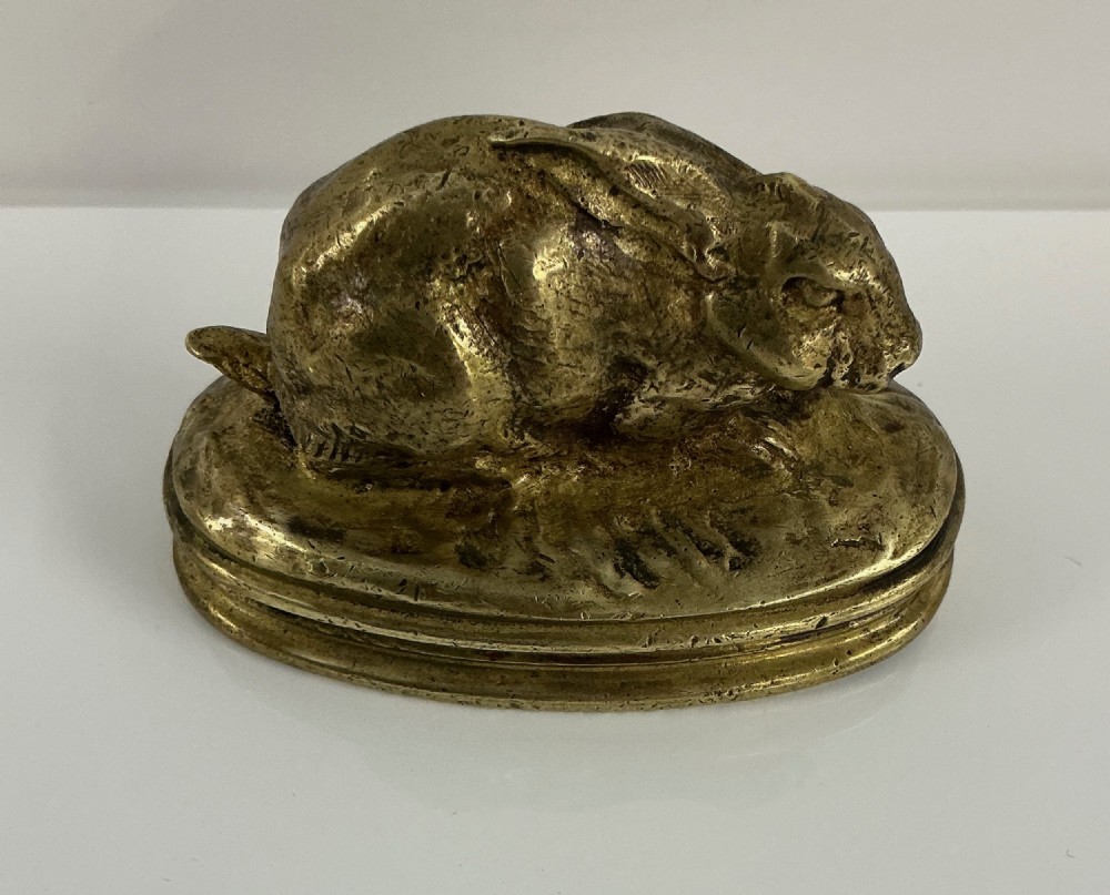 A small 19th-century gilt bronze sculpture depicting a crouching rabbit on an oval moulded base.