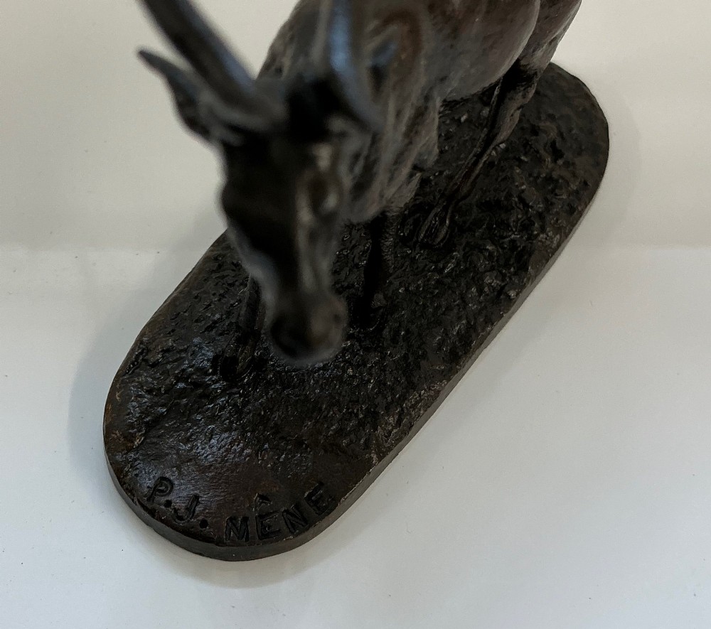 A dark patinated bronze sculpture of a standing stag with multi-pointed antlers, set on an oval textured base bearing a signature. View III