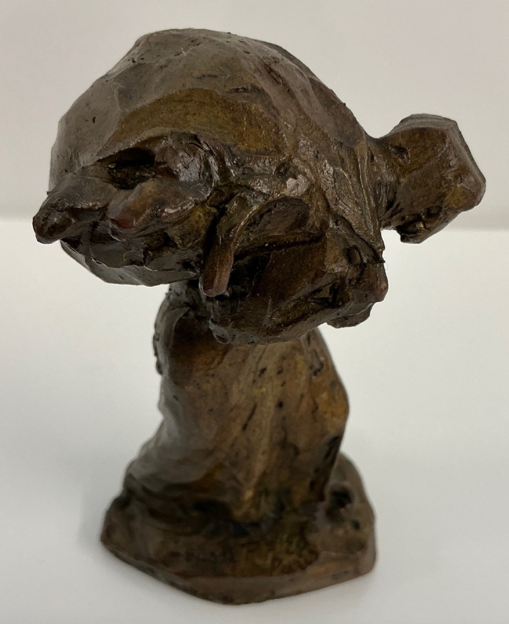 A patinated dark brown bronze sculpture by Jules Dalou depicting a bent female peasant figure carrying a heavy bundle.
