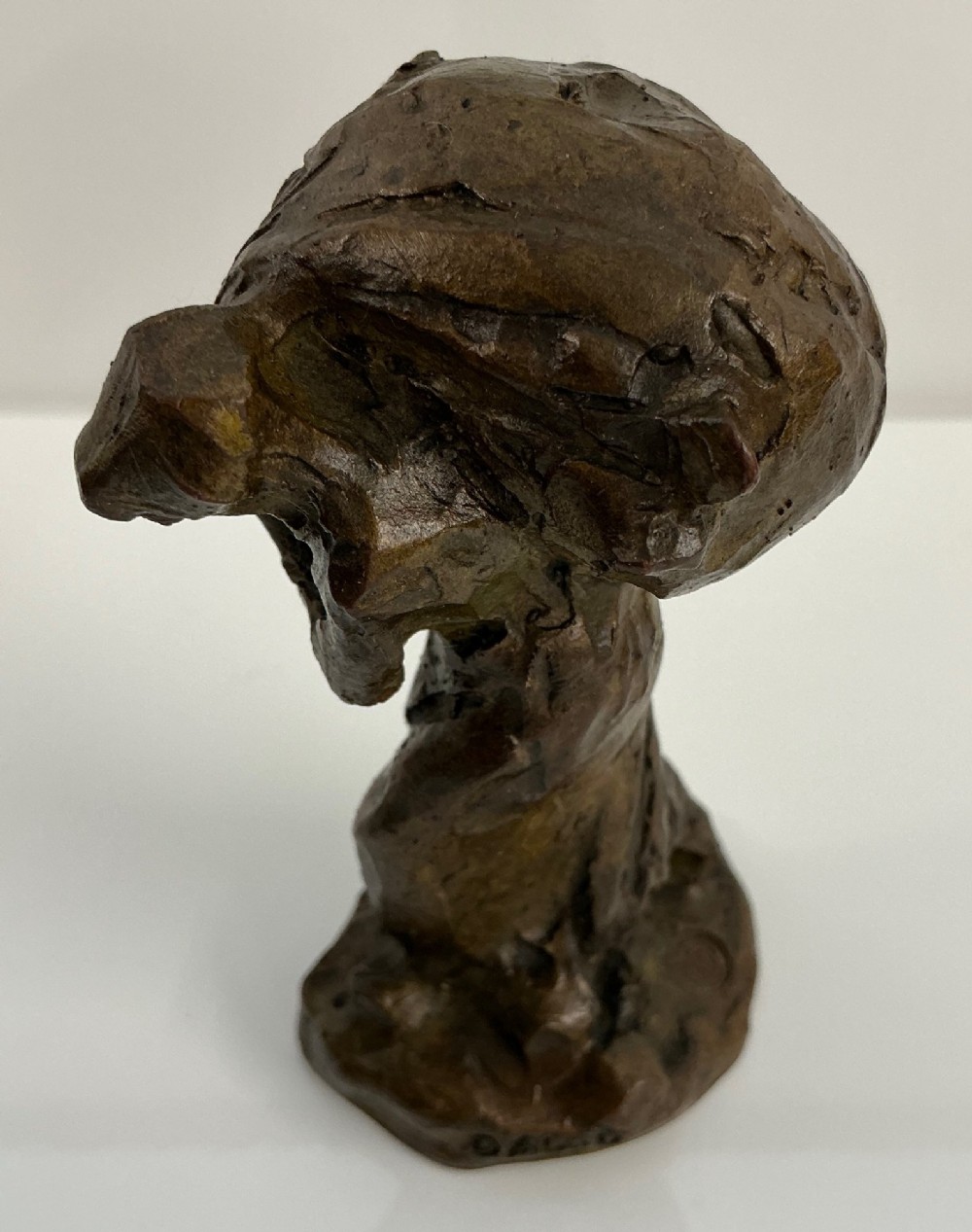 A patinated dark brown bronze sculpture by Jules Dalou depicting a bent female peasant figure carrying a heavy bundle. View II