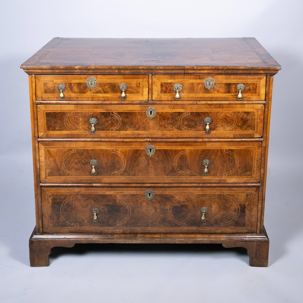 An early 18th-century inlaid walnut chest of drawers featuring two short over three long drawers, brass drop handles, and bracket feet. View II