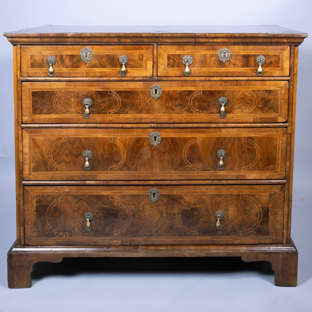 An early 18th-century inlaid walnut chest of drawers featuring two short over three long drawers, brass drop handles, and bracket feet. View III